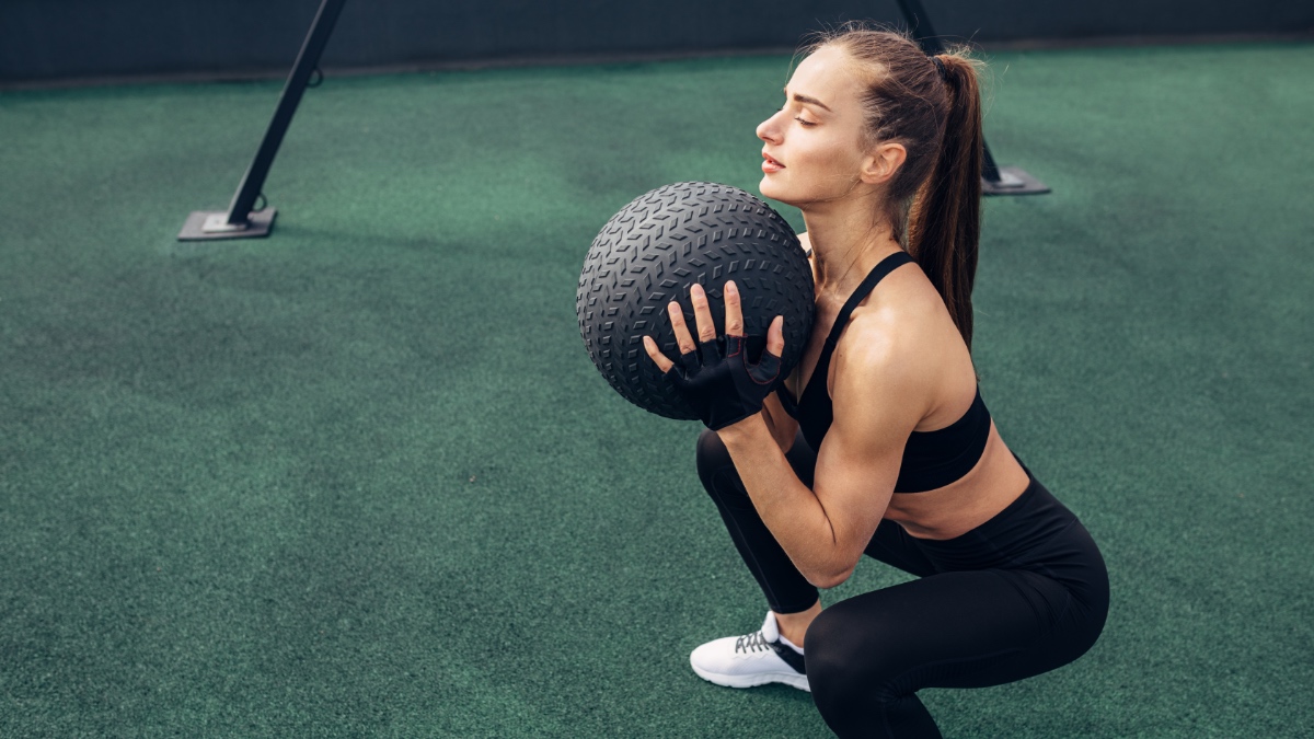 Ein Frau trainiert mit einem Medizinball.