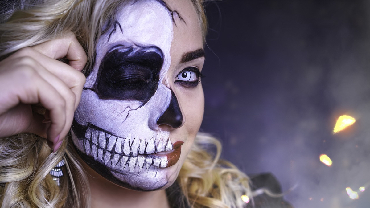 Eine blonde Frau in einem Halloween-Kostüm, die wie ein Skelett geschminkt ist.