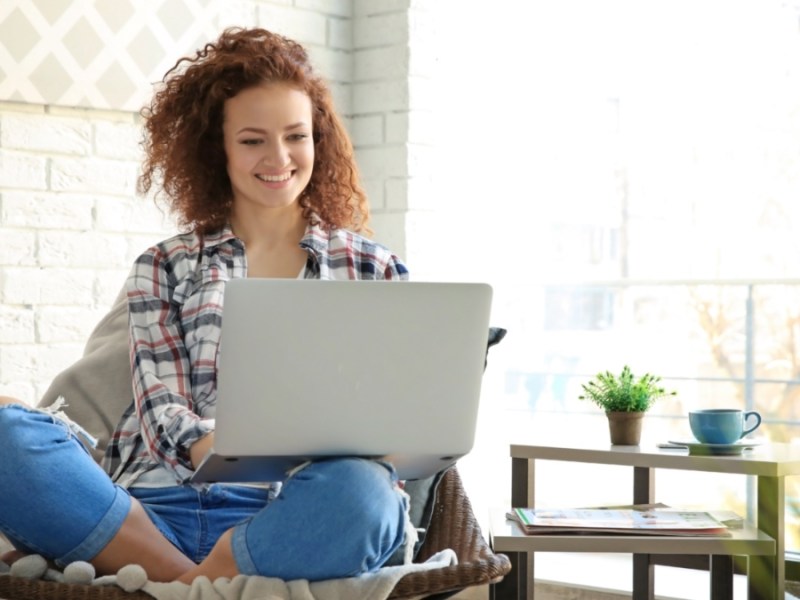 Eine junge Frau, die auf ihren Laptop schaut.