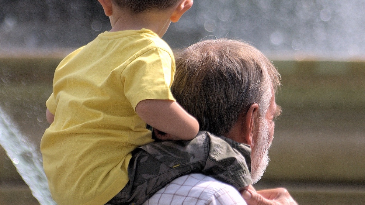 Ein Großvater trägt seinen Enkel Huckepack auf den Schultern.