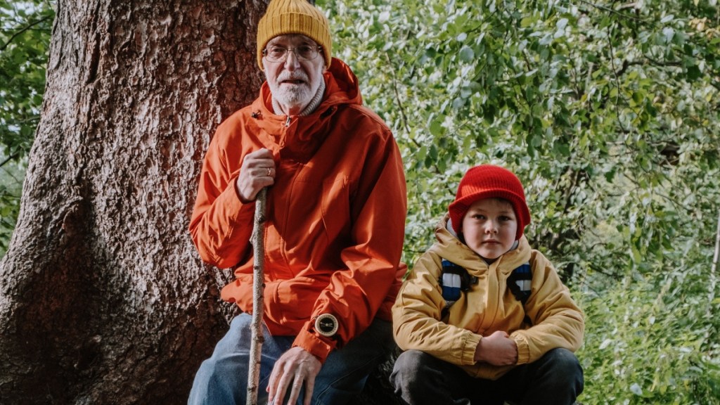 Ein Großvater wandert mit seinem Enkel in einem Wald.