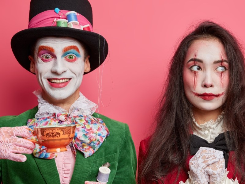 Ein Mann und eine Frau in Halloween-Kostümen vor einem pinken Hintergrund.