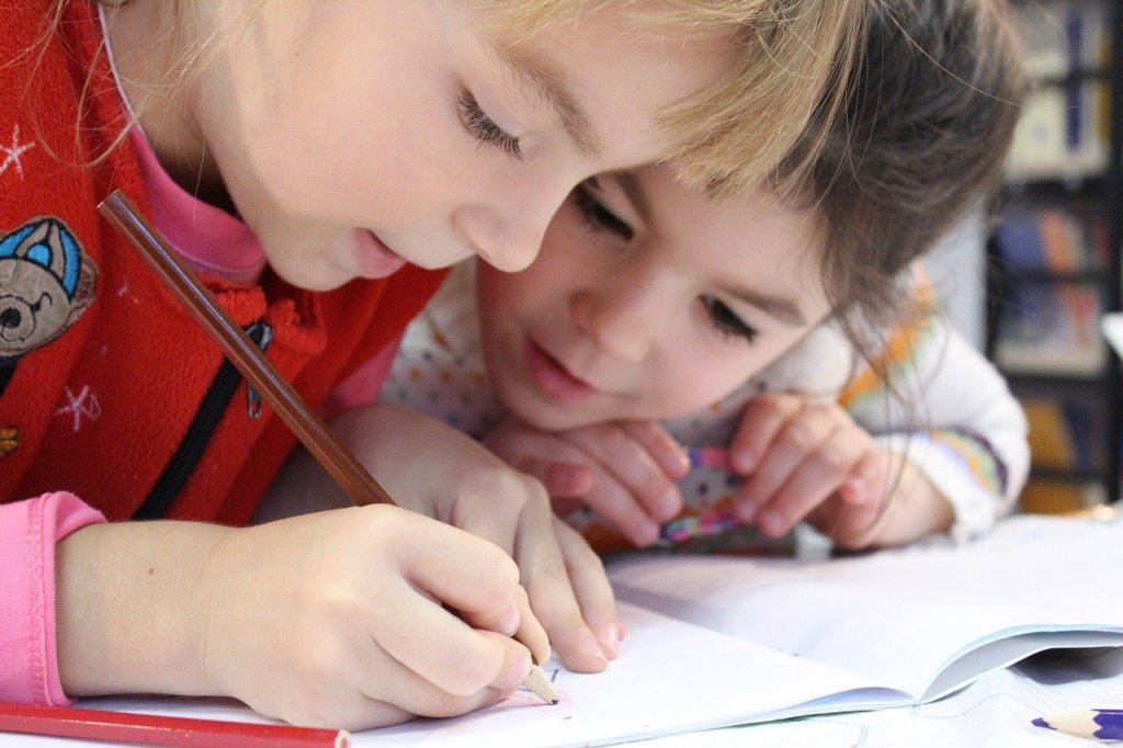 Zwei kleine Mädchen schreiben in ihrem Schulfheft.