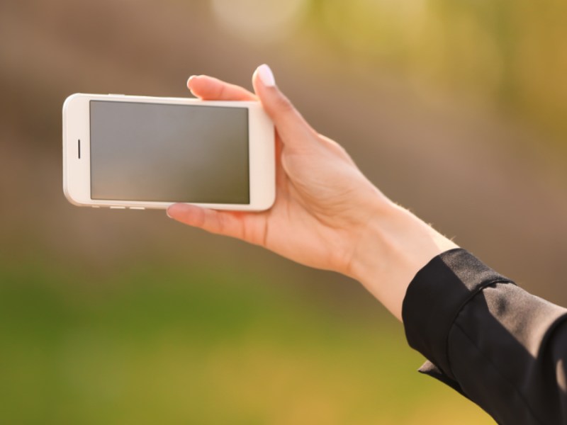 Eine junge Frau macht ein Selfie mit ihrem Smartphone.