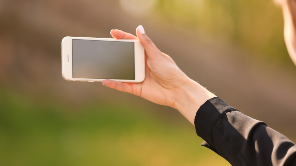 Eine junge Frau macht ein Selfie mit ihrem Smartphone.