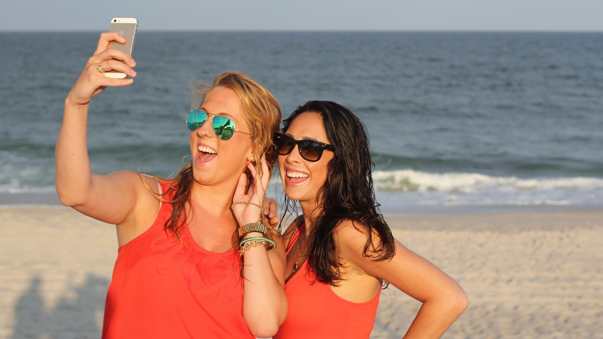 Zwei Freundinnen machen ein Selfie am Strand.