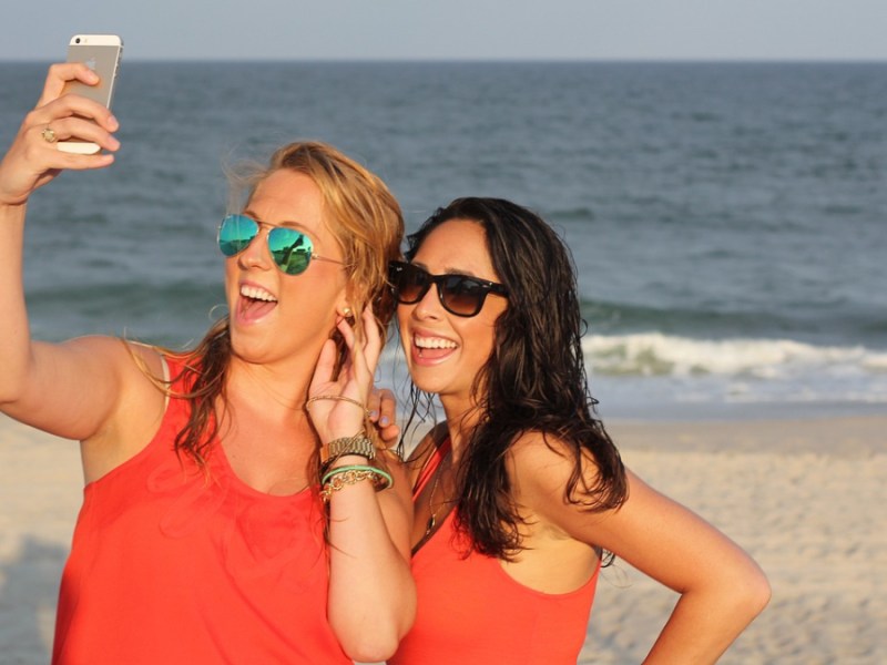 Zwei Freundinnen machen ein Selfie am Strand.