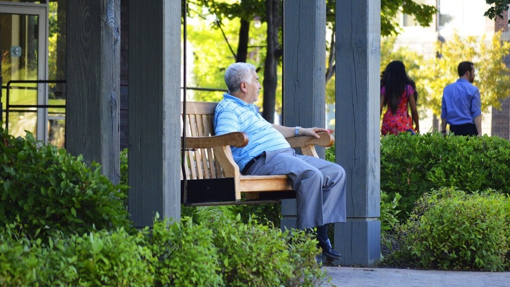 Ein alter Mann sitzt auf einer Parkbank