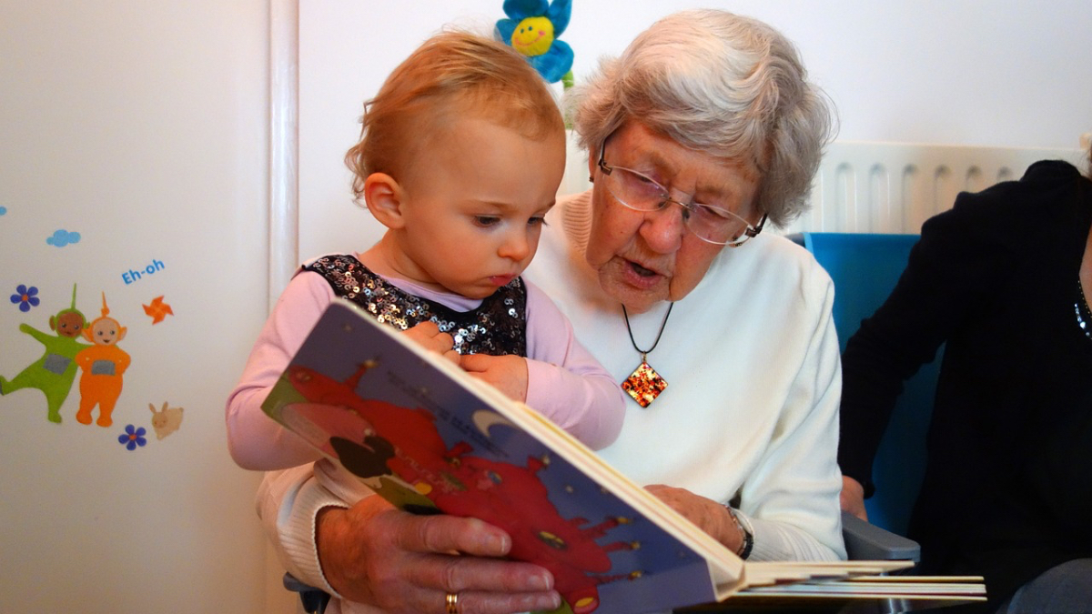 Eine Großmutter liest ihrer Enkelin etwas vor.