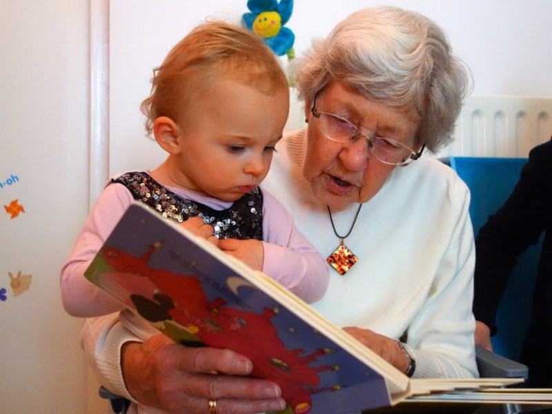 Eine Großmutter liest ihrer Enkelin etwas vor.