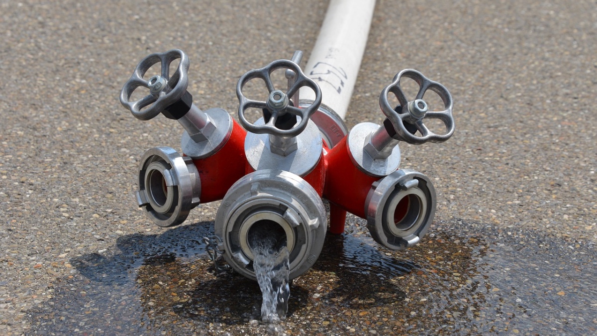 Ein Feuerwehrschlauch liegt auf der Straße und Wasser läuft heraus.