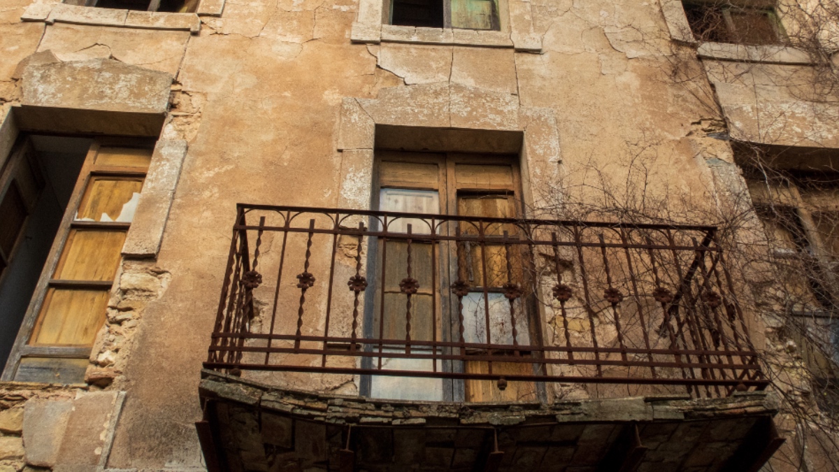 Ein Bild von einem maroden Balkon eines verfallenen Gebäudes.