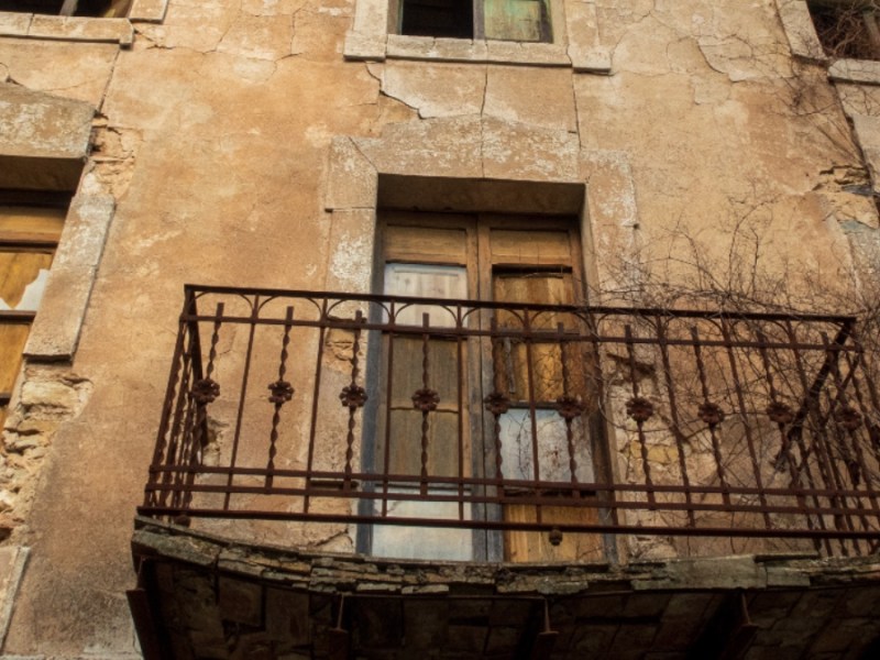 Ein Bild von einem maroden Balkon eines verfallenen Gebäudes.