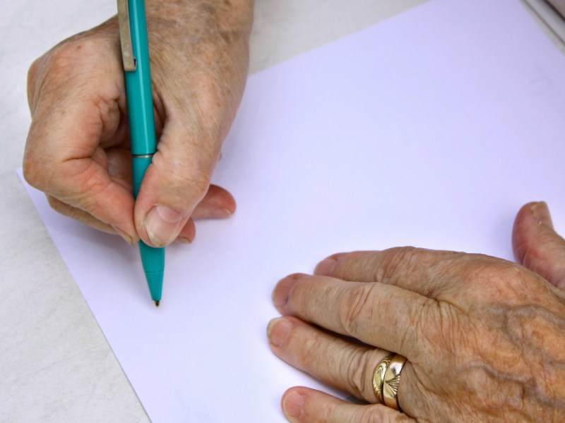 Eine alte Frau schreibt einen Brief.