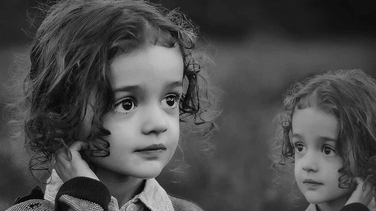 Ein kleines Mädchen in schwarzweiß neben ihrem Spiegelbild.