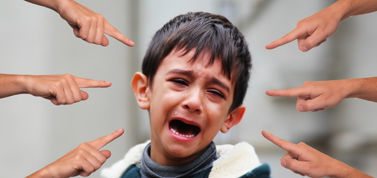 Sechs Finger zeigen auf ein weinendes Kind.