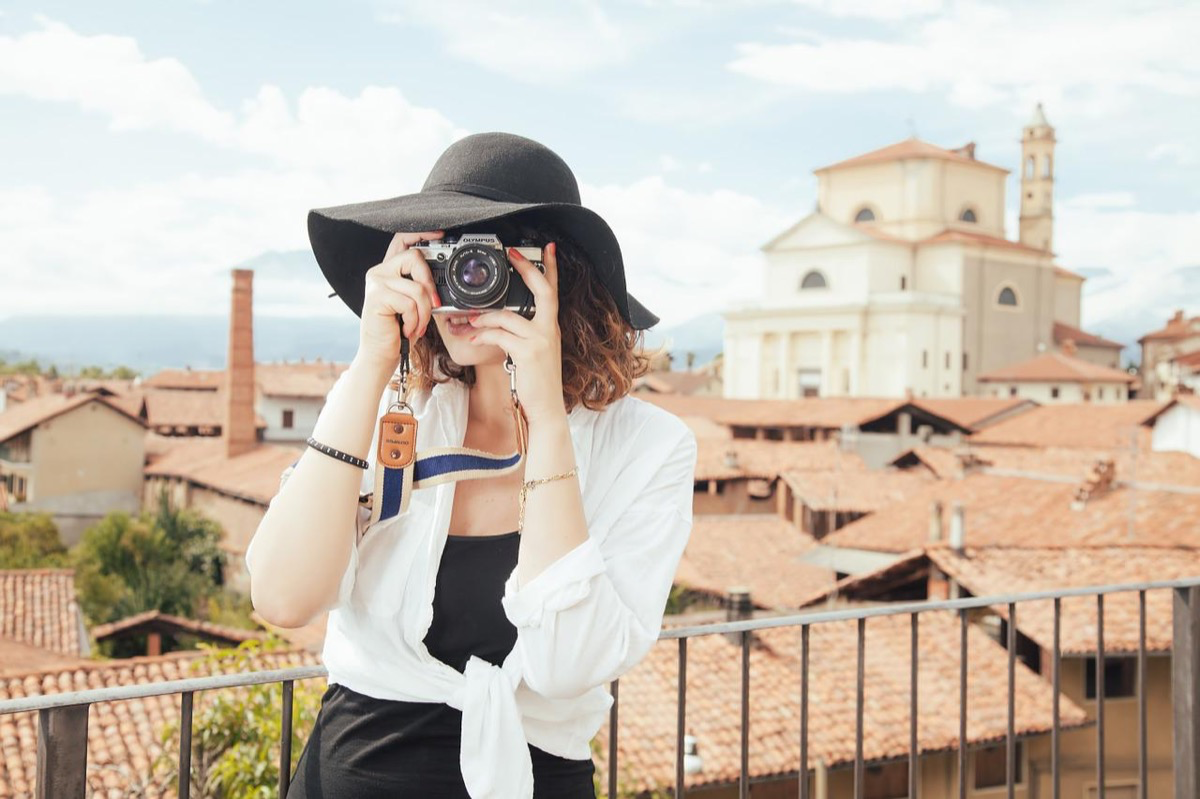Eine Touristin mit Hut und Kamera macht ein Foto