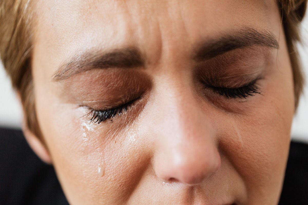 Eine weinende Frau mit Tränen im Gesicht.