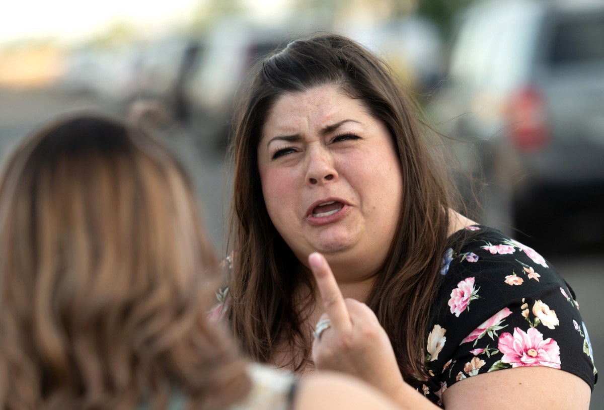Eine wütende Frau zeigt einer anderen Frau schimpfend den Mittelfinger.