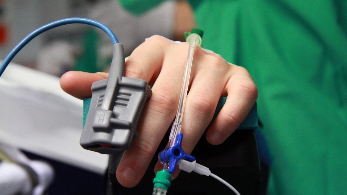 Ein Bild von der Hand eines Patienten in einem Krankenhaus, an der diverse Kanülen angeschlossen sind.