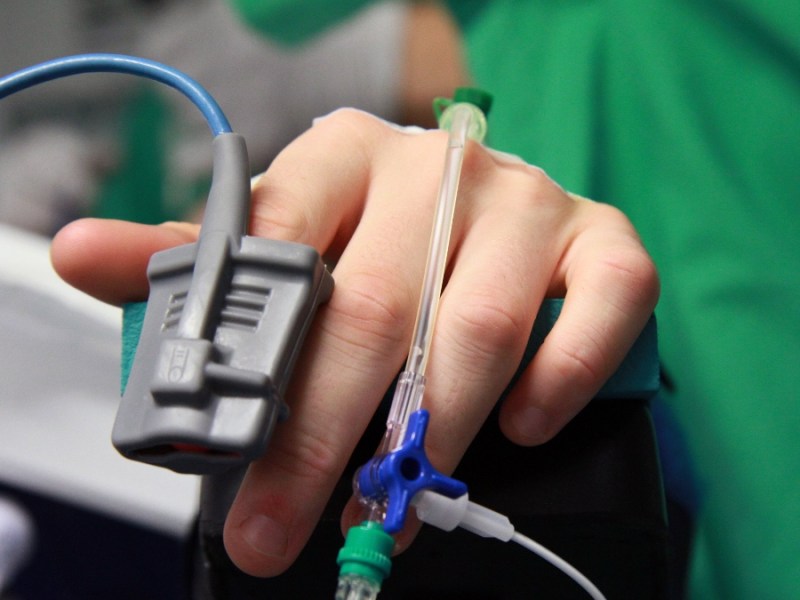Ein Bild von der Hand eines Patienten in einem Krankenhaus, an der diverse Kanülen angeschlossen sind.