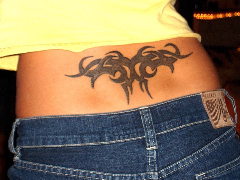 Ein Tribal-Tattoo auf dem unteren Rücken einer Frau.