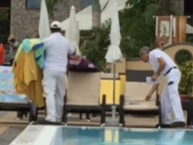 Hotelmitarbeiter entfernen Handtücher von Sonnenliege