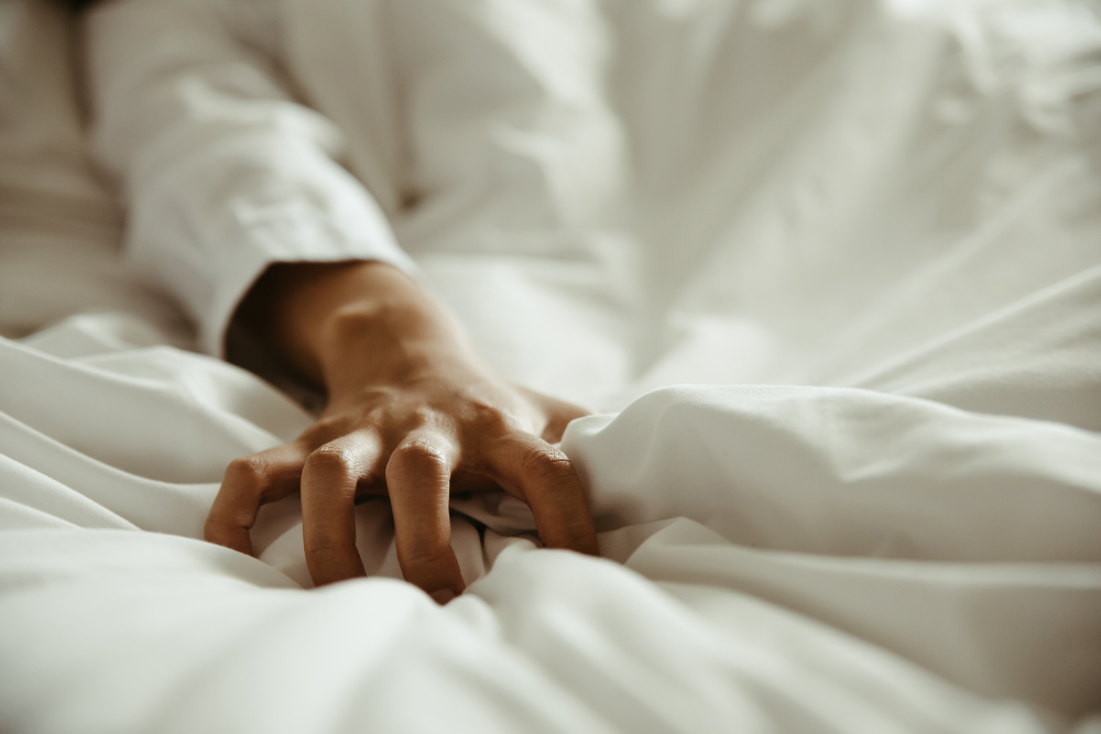 Eine Hand krallt sich in ein weißes Bettlaken