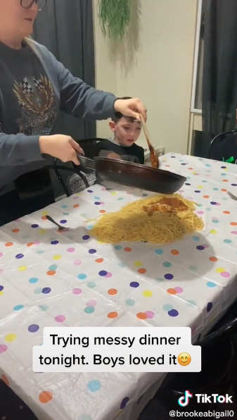 Eine Mutter richtet Spaghetti auf einem Wohnzimmertisch an.