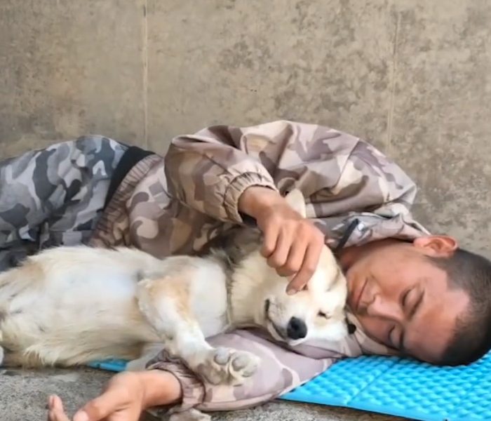 Ein Mann kuschelt mit seinem Hund auf einer Isomatte