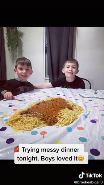 Zwei Kinder sitzen vor einem Berg Spaghetti, der auf einem Tisch angerichtet ist.