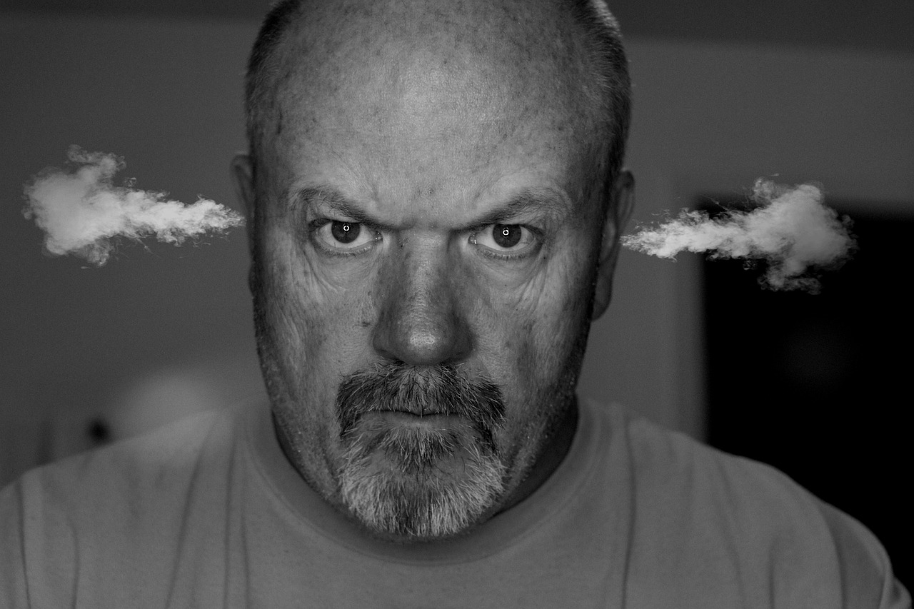 Ein Schwarzweißbild von einem wütenden Mann, dem Dampf aus den Ohren kommt.