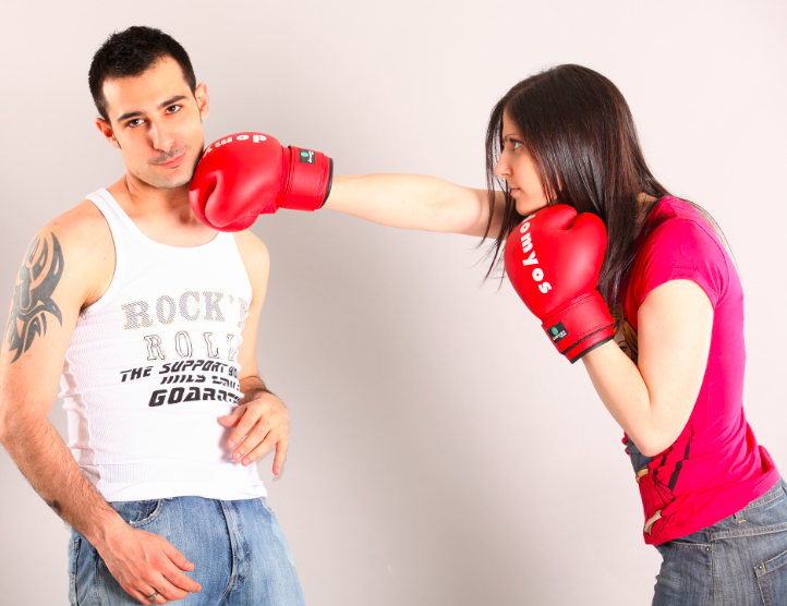Partnerin boxt Mann mit Boxhandschuh ins Gesicht