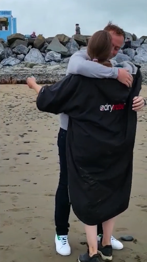 Ein Mann umarmt eine Frau an einem Strand.