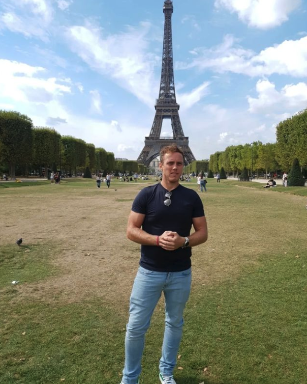 Ein Porträt von einem jungen Mann vor dem Eiffelturm.