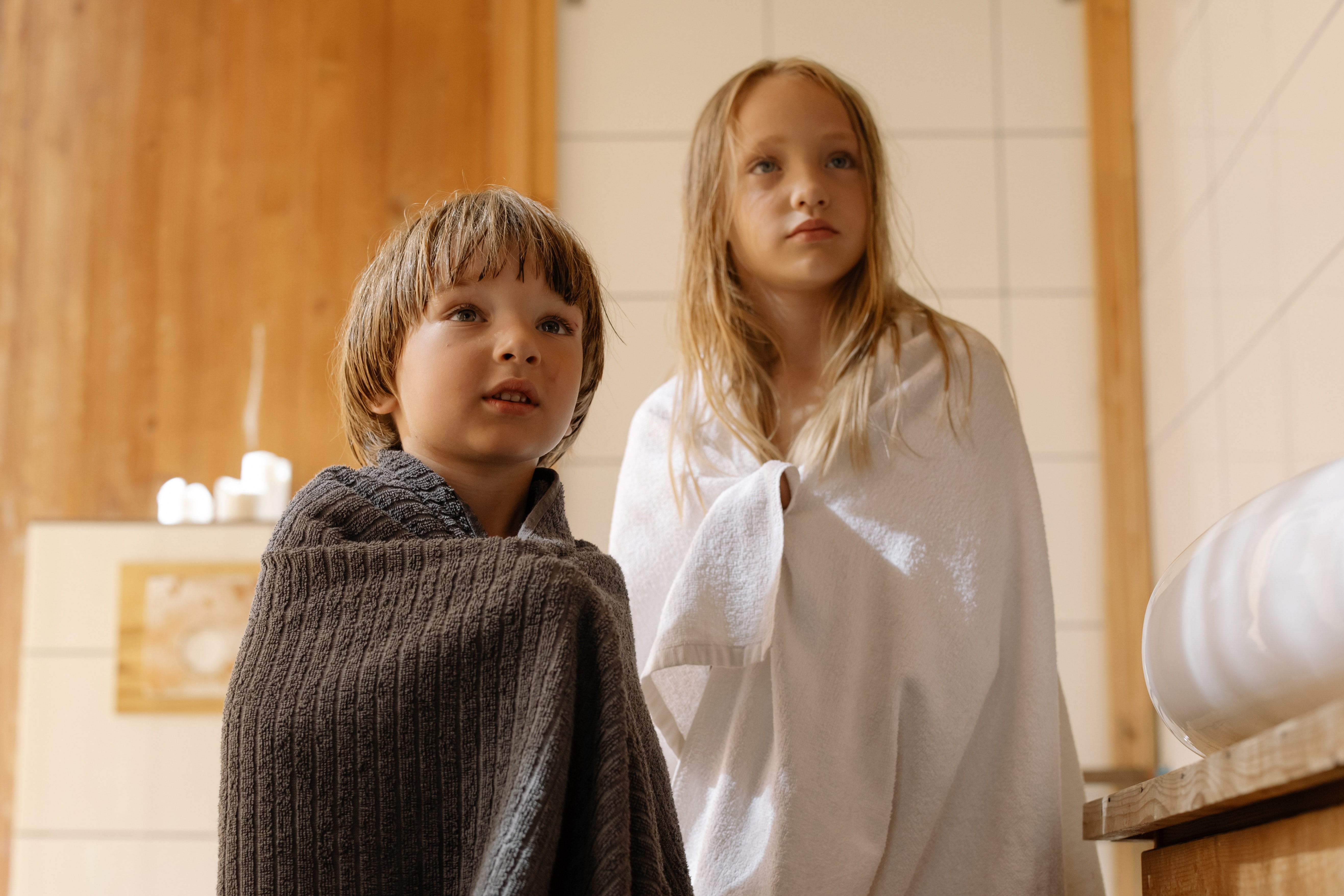 Junge und Mädchen stehen im Bad, eingehüllt in ein Handtuch.