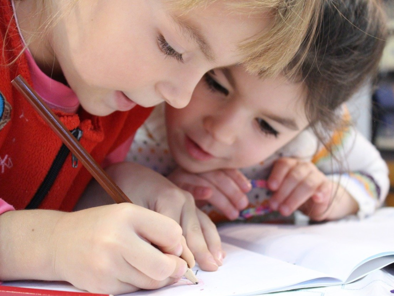 Zwei Grunschulkinder schreiben in Heft