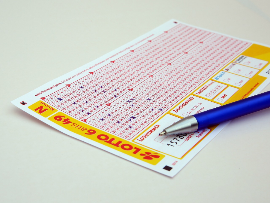 Ein ausgefüllter Lottoschein und ein Kugelschreiber liegen auf einem Tisch.