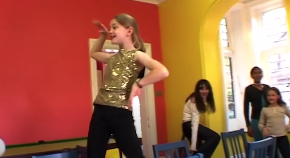 Ein Mädchen tanzt vor den Augen dreier Mädchen, die zuschauen.