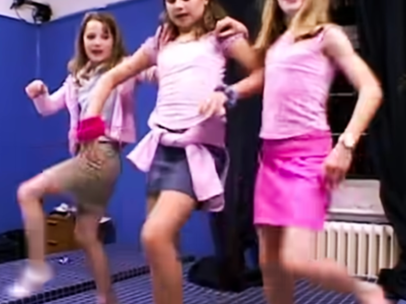 Drei junge Mädchen, die in einer Reihe tanzen.