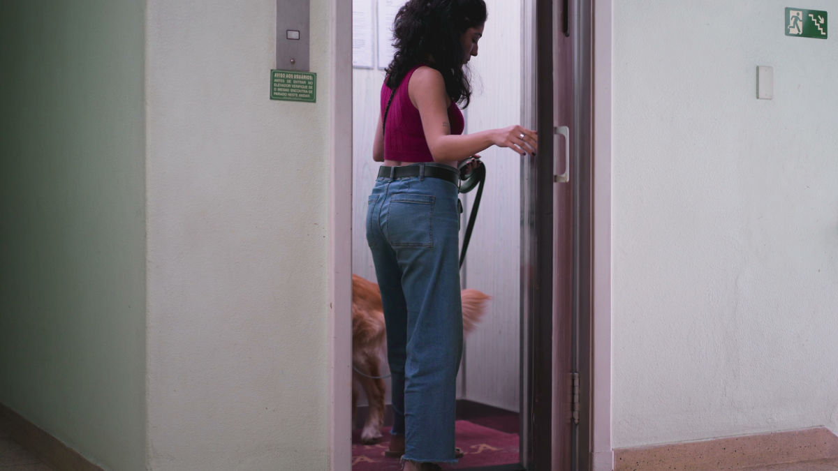 Eine Frau mit einem Hund an der Leine steht in einem Fahrstuhl.