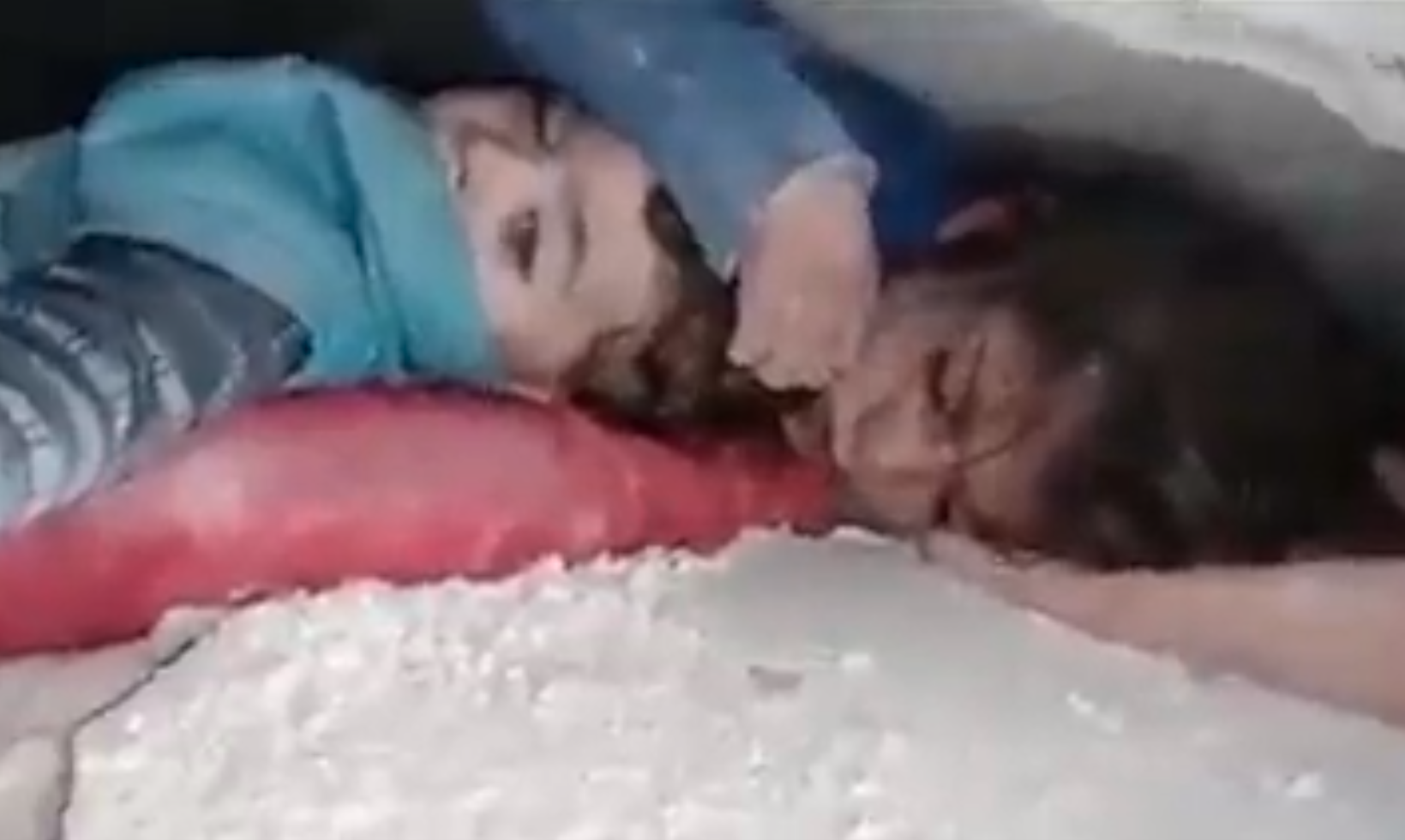 Ein kleines Mädchen wurde unter den Trümmern eines Hauses in Syrien begraben. Sie schützt den Kopf ihres kleinen Bruders mit der Hand.