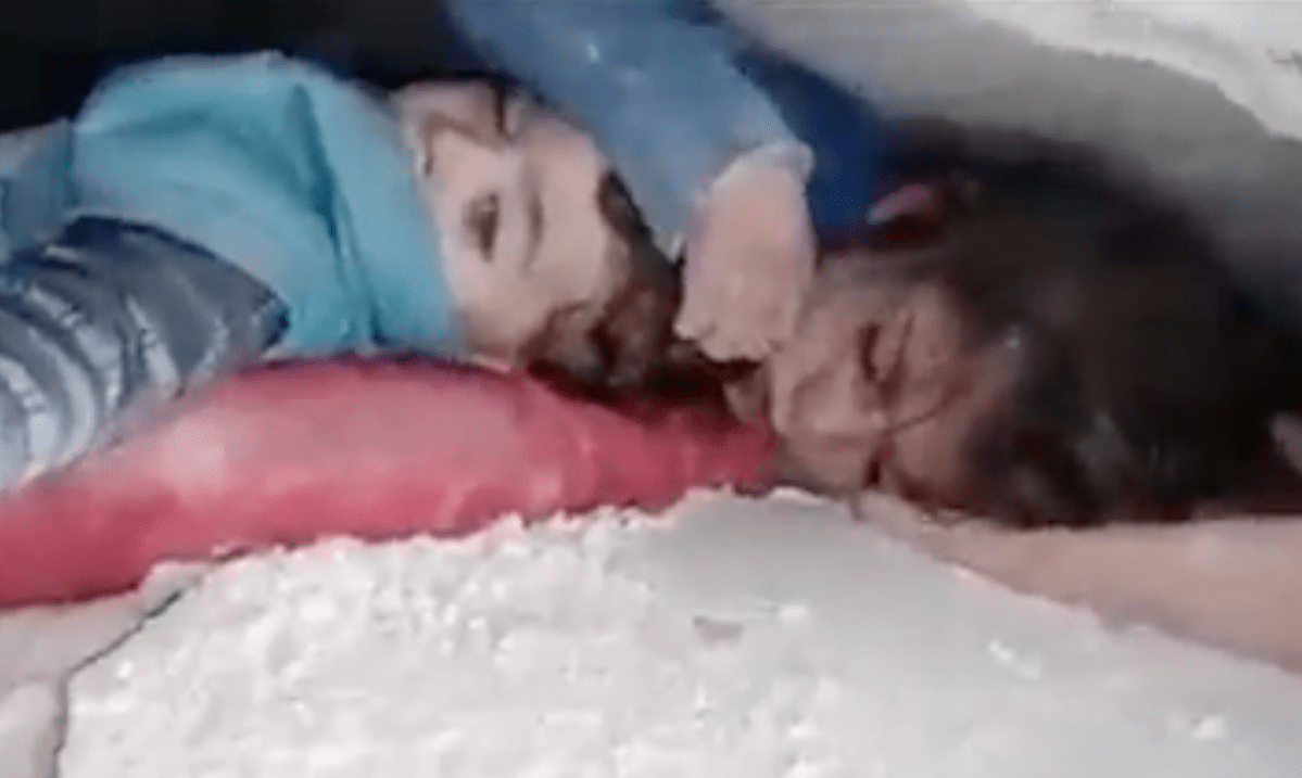Ein kleines Mädchen wurde unter den Trümmern ihres Hauses in Syrien begraben. Sie schützt den Kopf ihres kleinen Bruders mit der Hand.