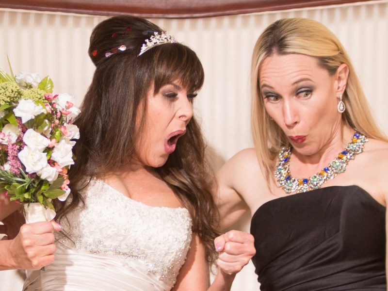 Eine Braut und eine Freundin machen schockierte Gesichter.