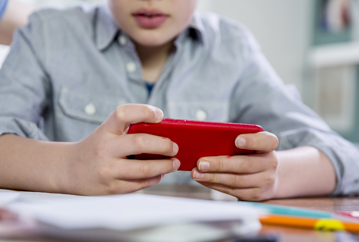 Ein blonder 10jähriger Junge spielt Videospiele auf seinem Handy.