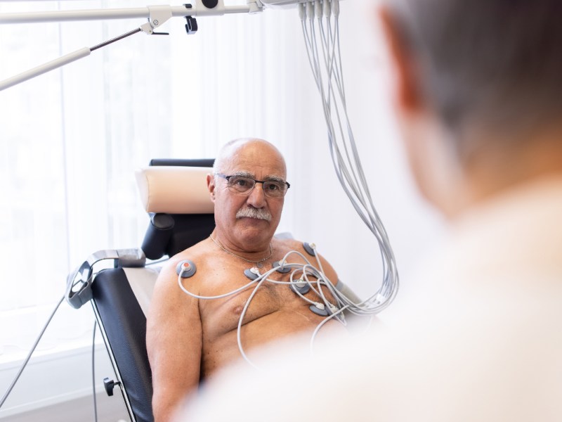 Ein älterer Patient mit freiem Oberkörper bekommt ein EKG.