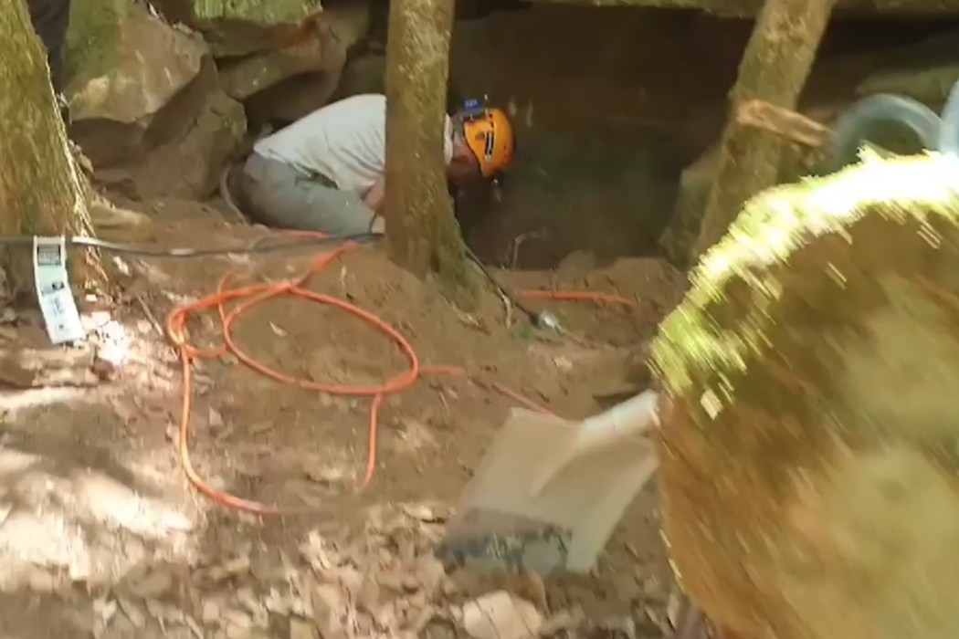 Ein Mann versucht, einen Hund aus einer Höhle zu befreien.