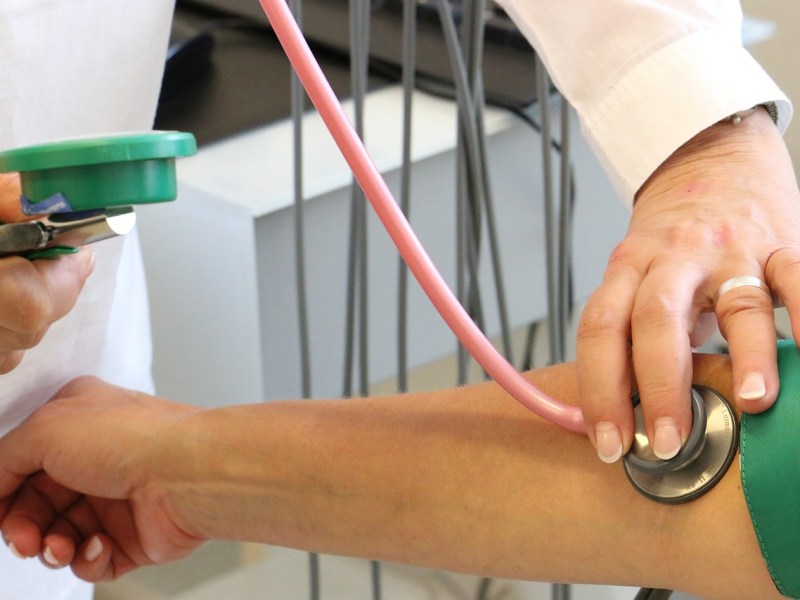 Ein Arzt misst den Blutdruck eines Patienten mit einem Stethoskop.