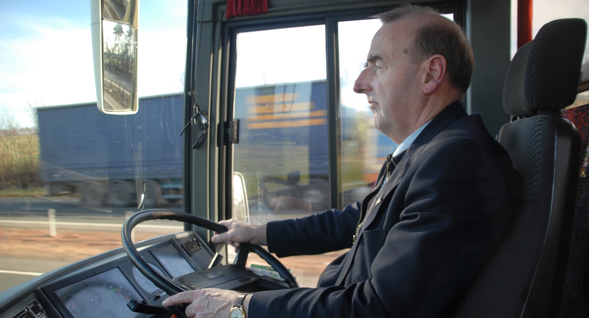 Ein Busfahrer sitzt am Steuer und lenkt einen Bus.