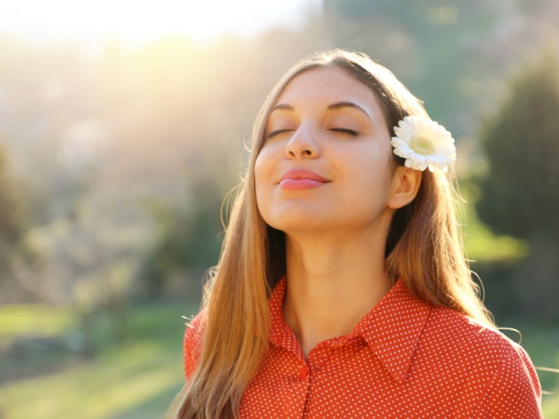 Eine hübsche junge Frau mit einer weißen Blume hinter dem Ohr.